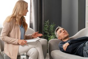 mid-shot-man-laying-couch-therapy-cabinet-near-woman-counselor